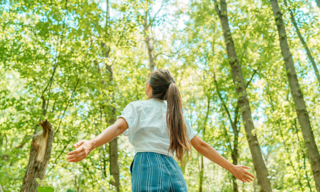 Woman breathing in nature and feeling free. If you're unsure what a top-down or bottom-up approach is for you, learn from a trauma therapy. Both somatic therapy and cognitive therapy have benefits. Learn more!
