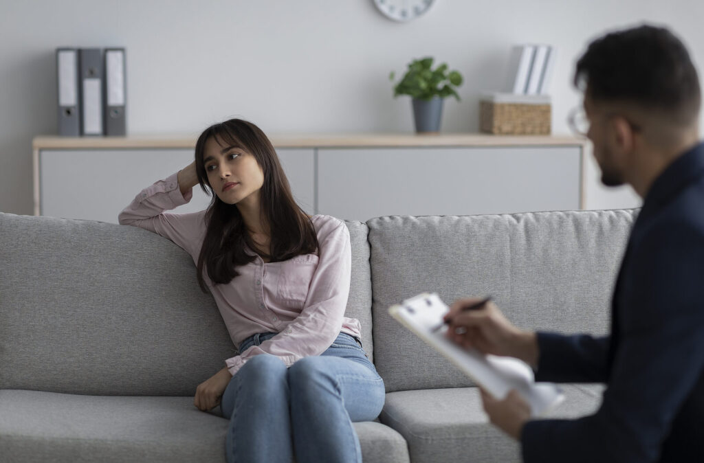 Woman on couch looking off into distance. When you have a trauma therapist who understands trauma-informed care, you are more inclined to feel safe. Find a trauma therapist near me who gets it. Montgomery, Al 36109 | San Diego, CA 92101| Denver, CO 80202
