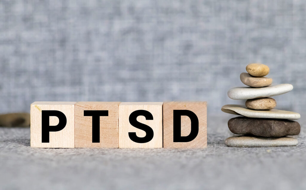 Image of PTSD spelled out on wood blocks next to a stack of rocks. Deal with complex PTSD dissociation with trauma-informed care. EMDR therapy can help. Start trauma therapy in Birmingham, Al 10337. Or trauma therapy in Montgomery, Al 36109. Look now to “find a trauma therapist near me” 
