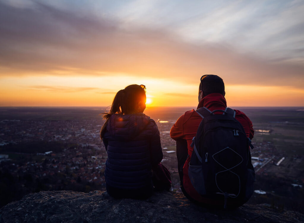 Photo of a woman and man watching the sunrise. This photo represents how understanding attachment and trauma can help you build healthier relationships.